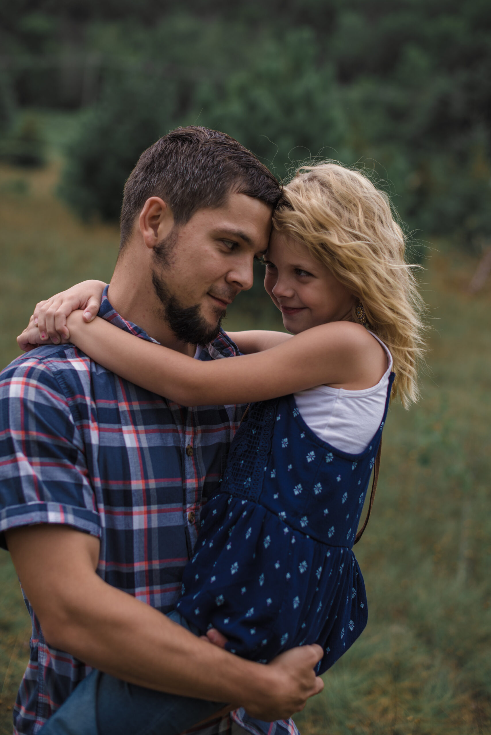 father and daughter hugging in field for family portraits in traverse city michigan