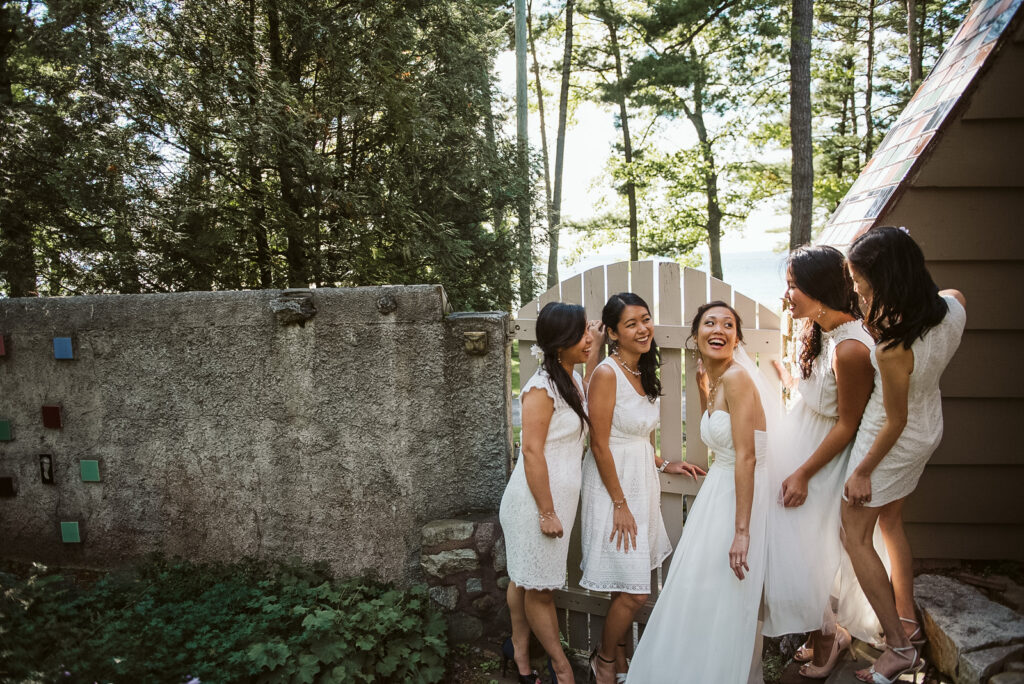 Traverse-City-Michigan-Wedding-Photographer-34 bride and her bridesmaids hiding at wedding venue in peninsula room traverse city
