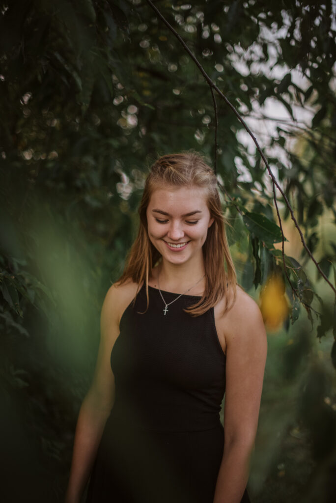high school senior in trees during senior pictures in traverse city photographer
