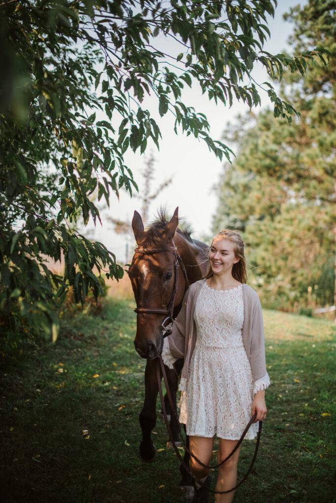 high school senior walking with horse during senior pictures in traverse city photographer