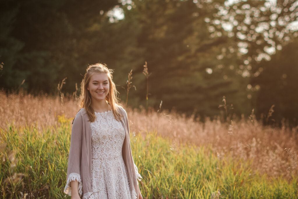 high school senior sitting in field during senior pictures in traverse city photographer