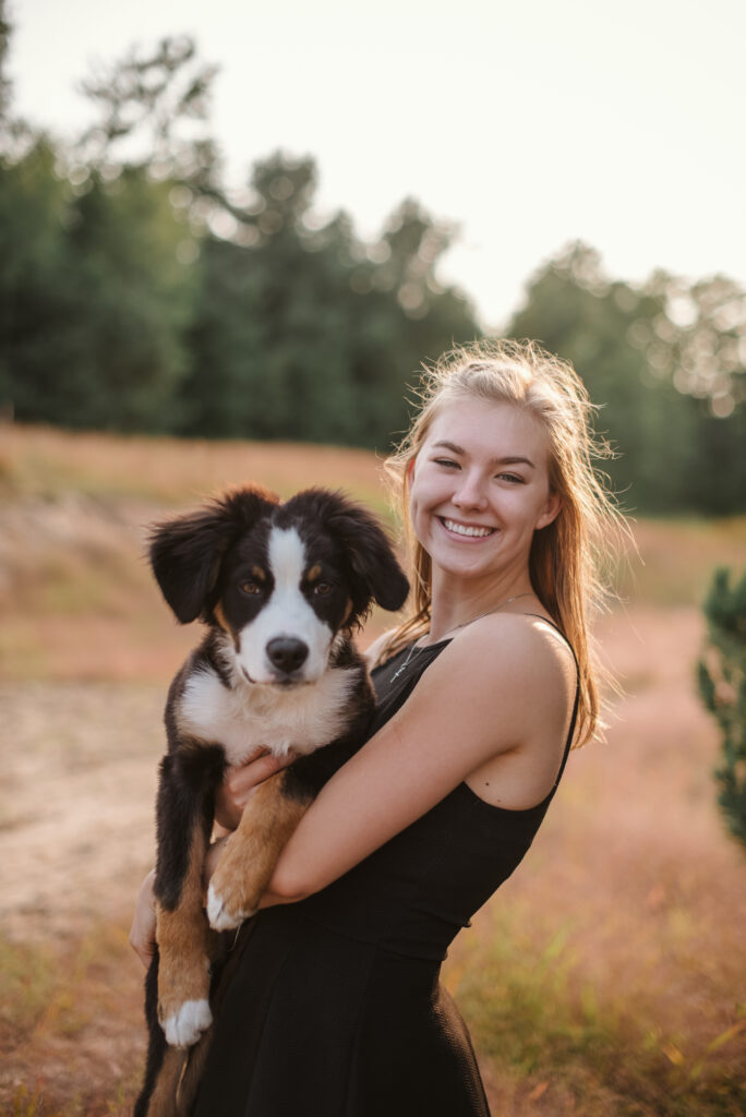 high school senior with dog in field during senior pictures in traverse city photographer
