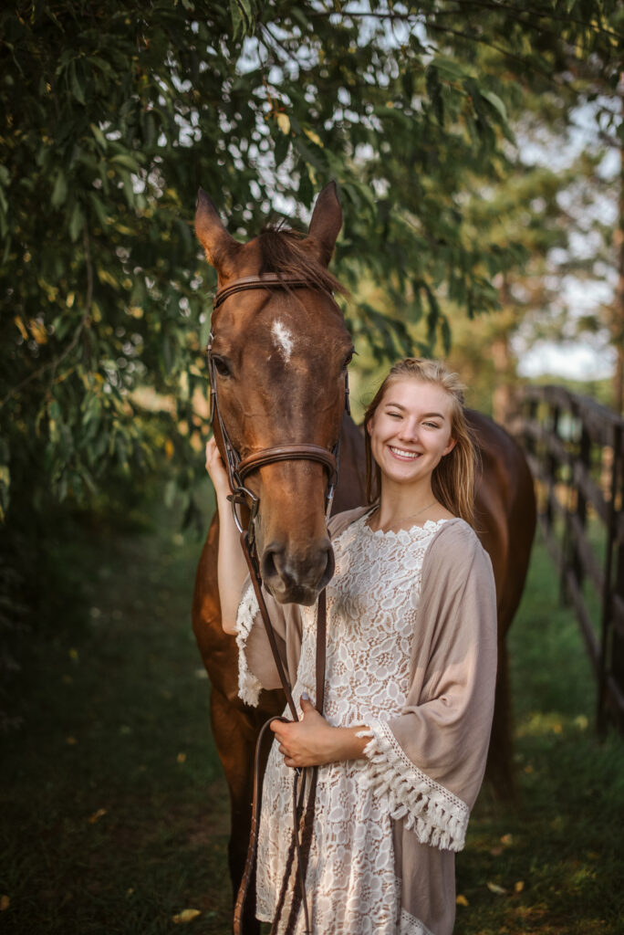 high school senior sitting in field during senior pictures in traverse city photographer