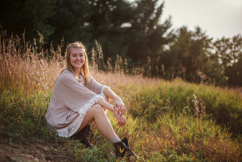 high school senior sitting in field during senior pictures in traverse city photographer