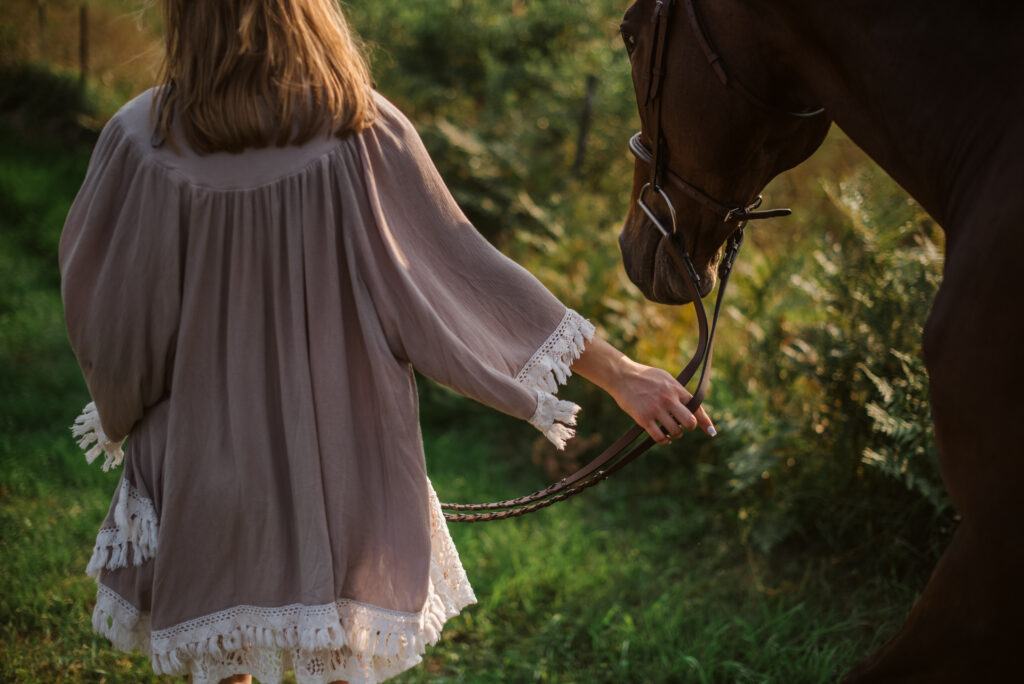 high school senior walking with horse during senior pictures in traverse city photographer