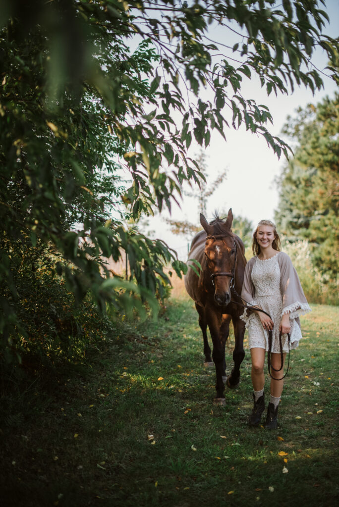 high school senior walking with horse during senior pictures in traverse city photographer