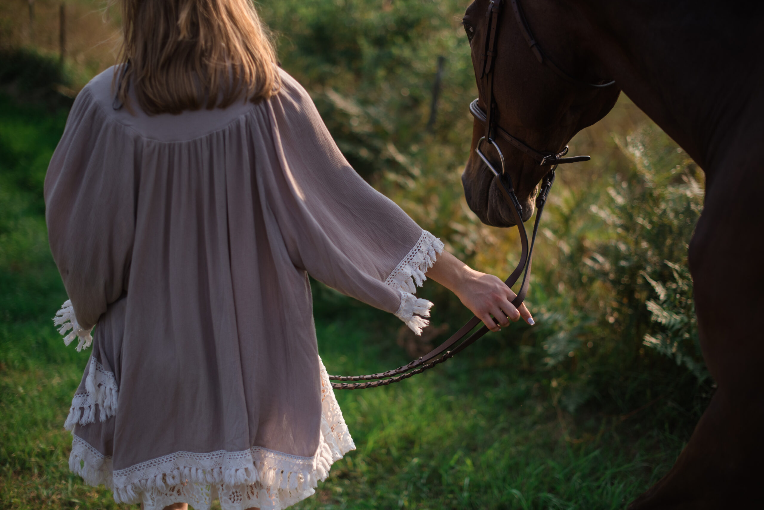 Grand Traverse Academy Senior standing with horse in barn during sunset during senior pictures in traverse city