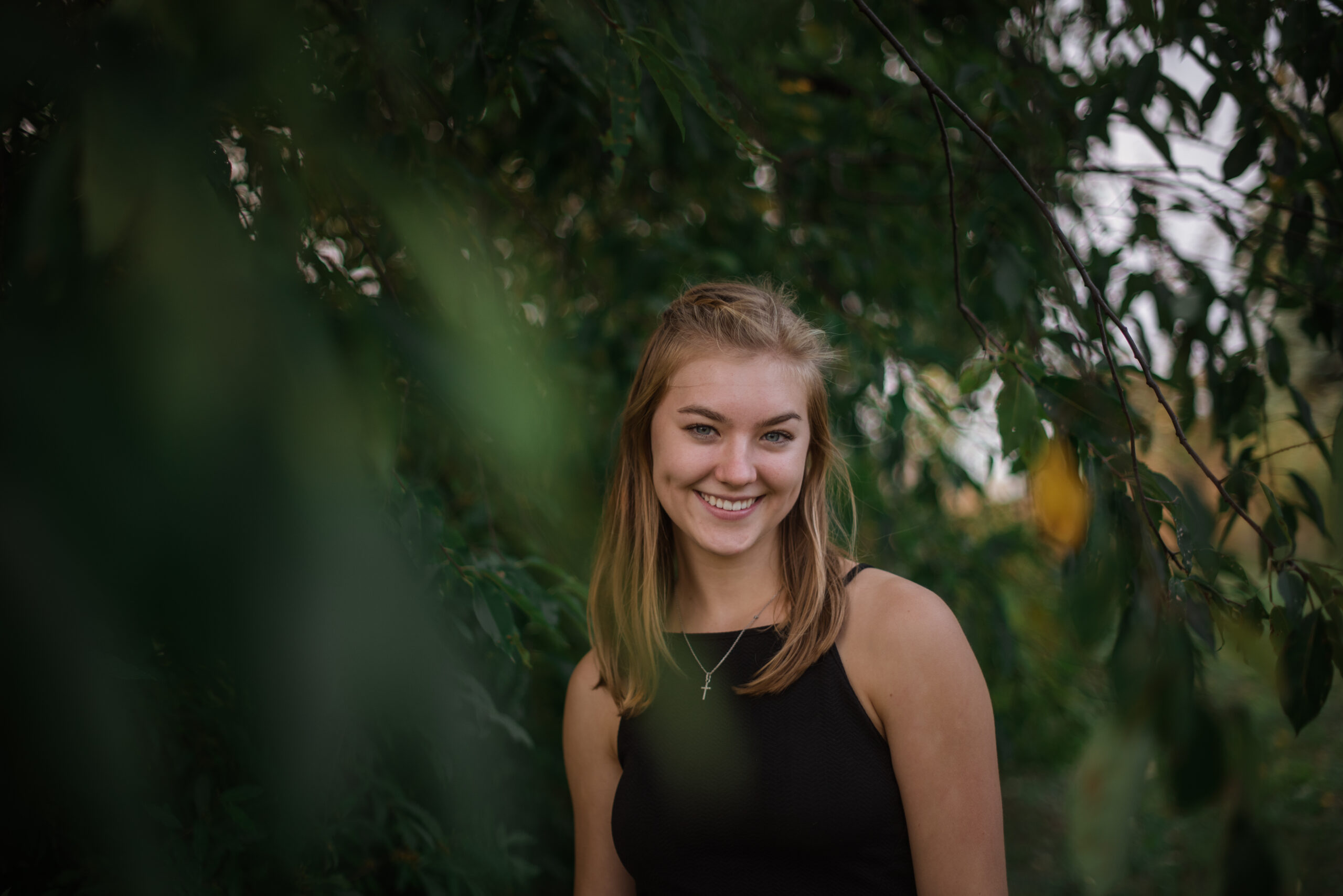 Grand Traverse Academy Senior standing under willow tree during senior photos in traverse city