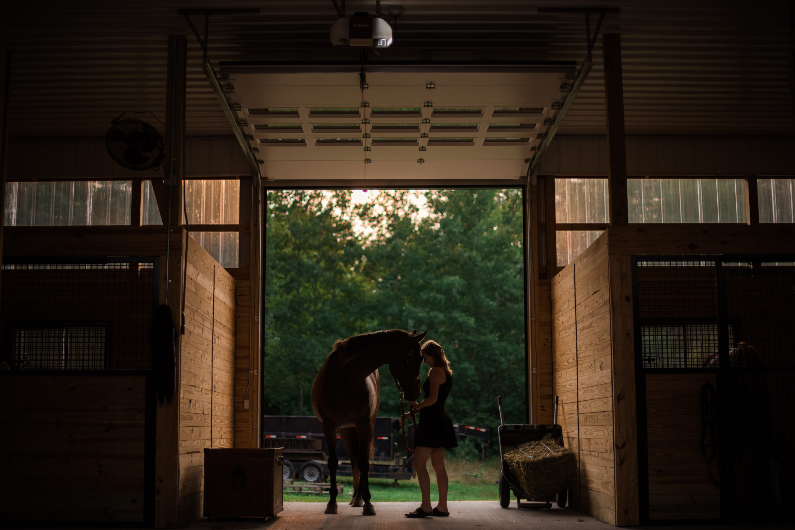 Traverse-City-Senior-Portraits-Horse36 Grand Traverse Academy Senior standing with horse in barn during sunset during senior photos in traverse city