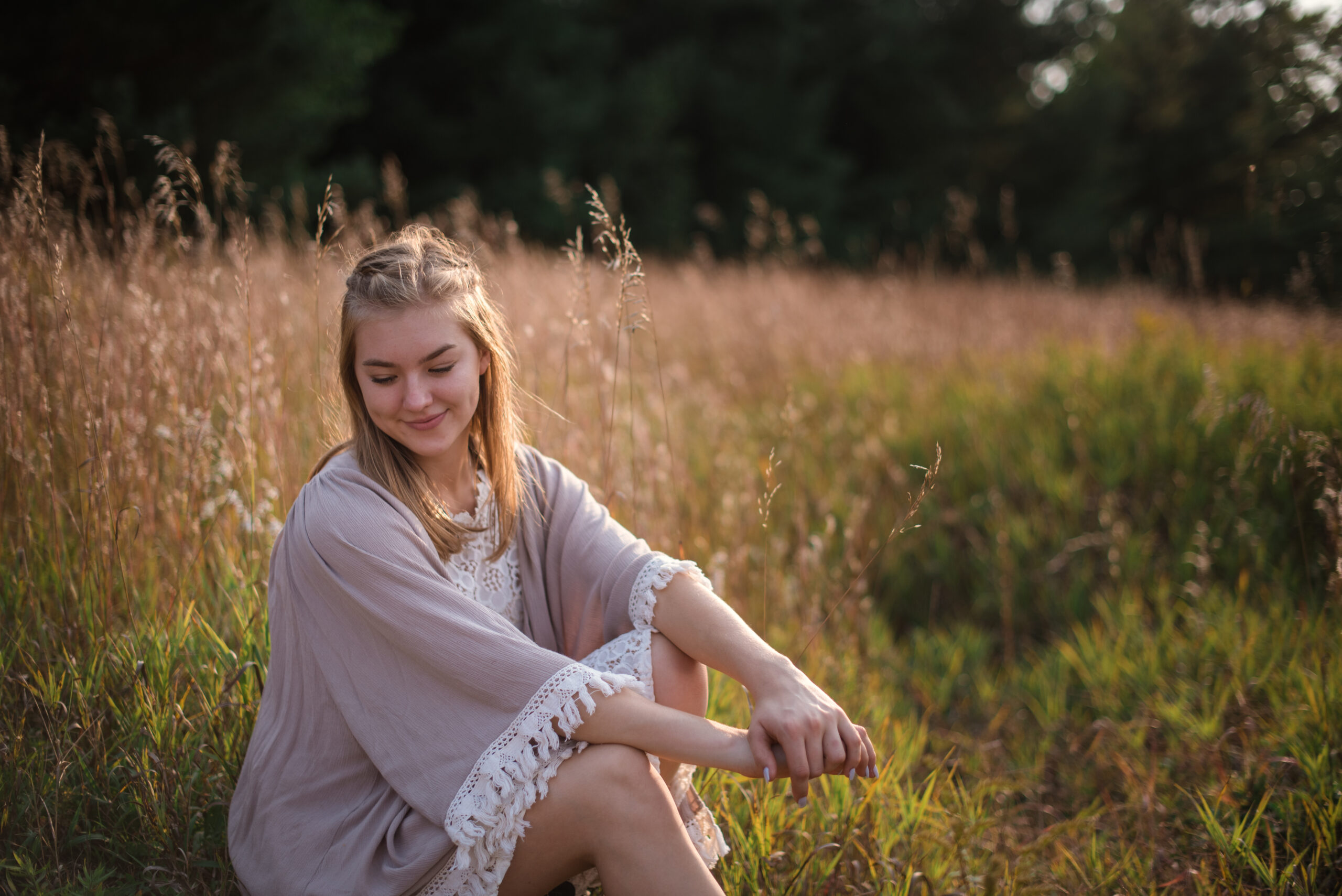 traverse city senior photo of girl sitting in field during golden hour