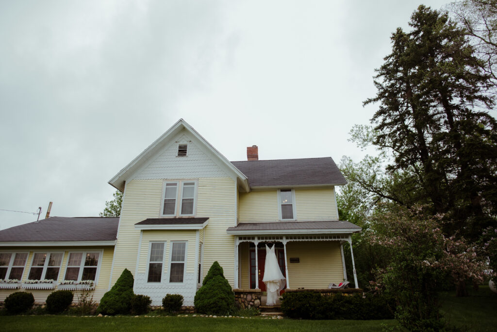 dress hanging from porch on farm house at barn wedding in traverse city michigan