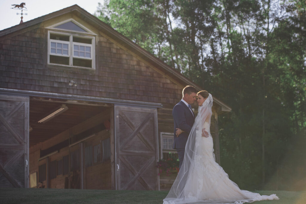 bride and groom standing in front of barn in traverse city michigan