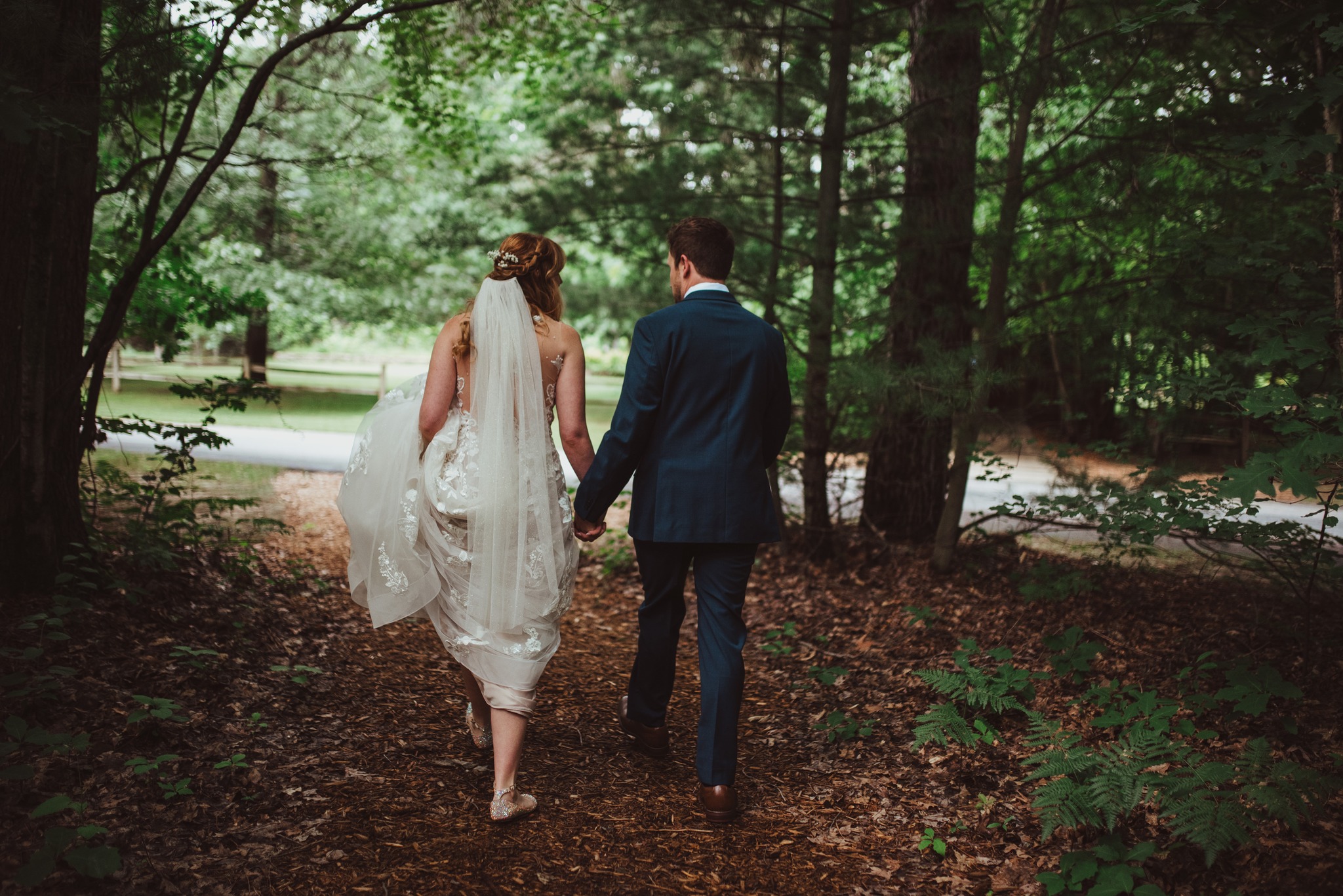 bride and groom candid walking through woods at wedding at blue bridge events center interlochen michigan