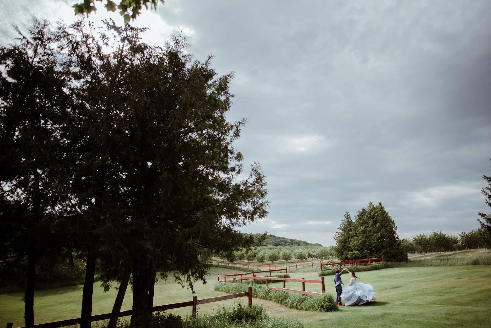 bride and groom dancing in open field next to barn in traverse city wedding