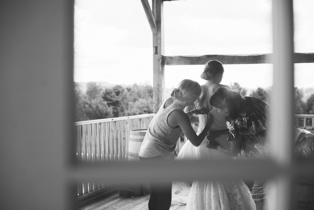bride and bridesmaids getting ready behind glass door at barn wedding in traverse city michigan