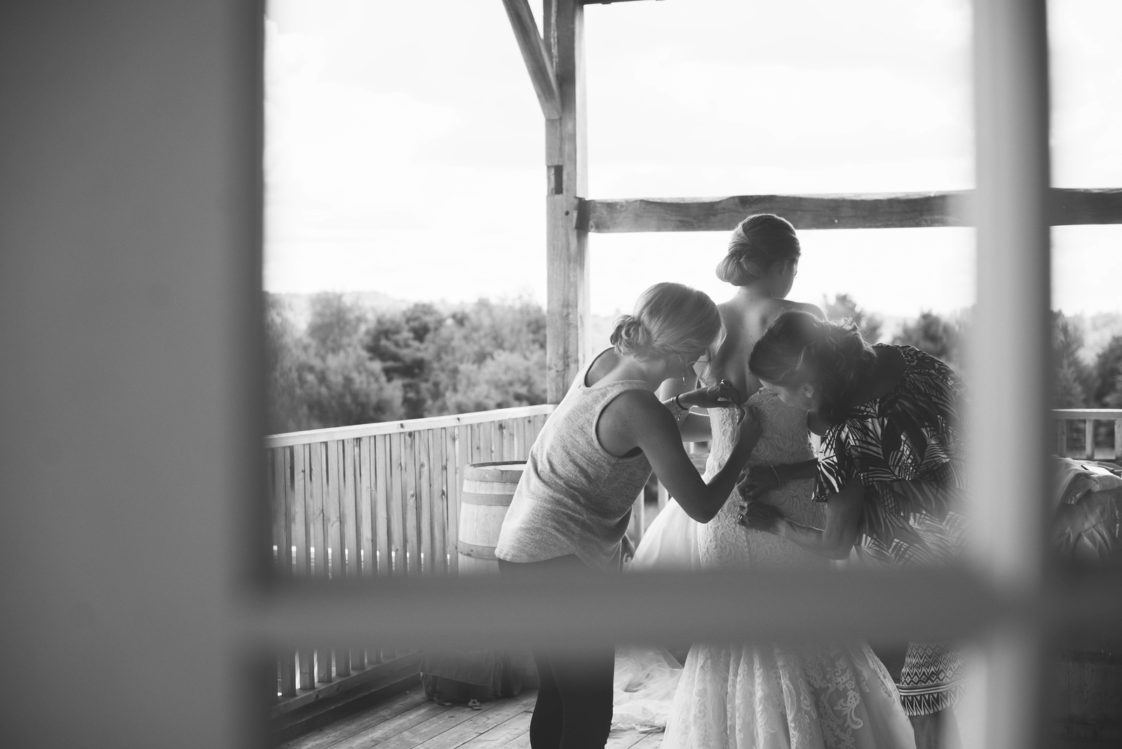 bride and bridesmaids getting ready behind glass door at barn wedding in traverse city michigan