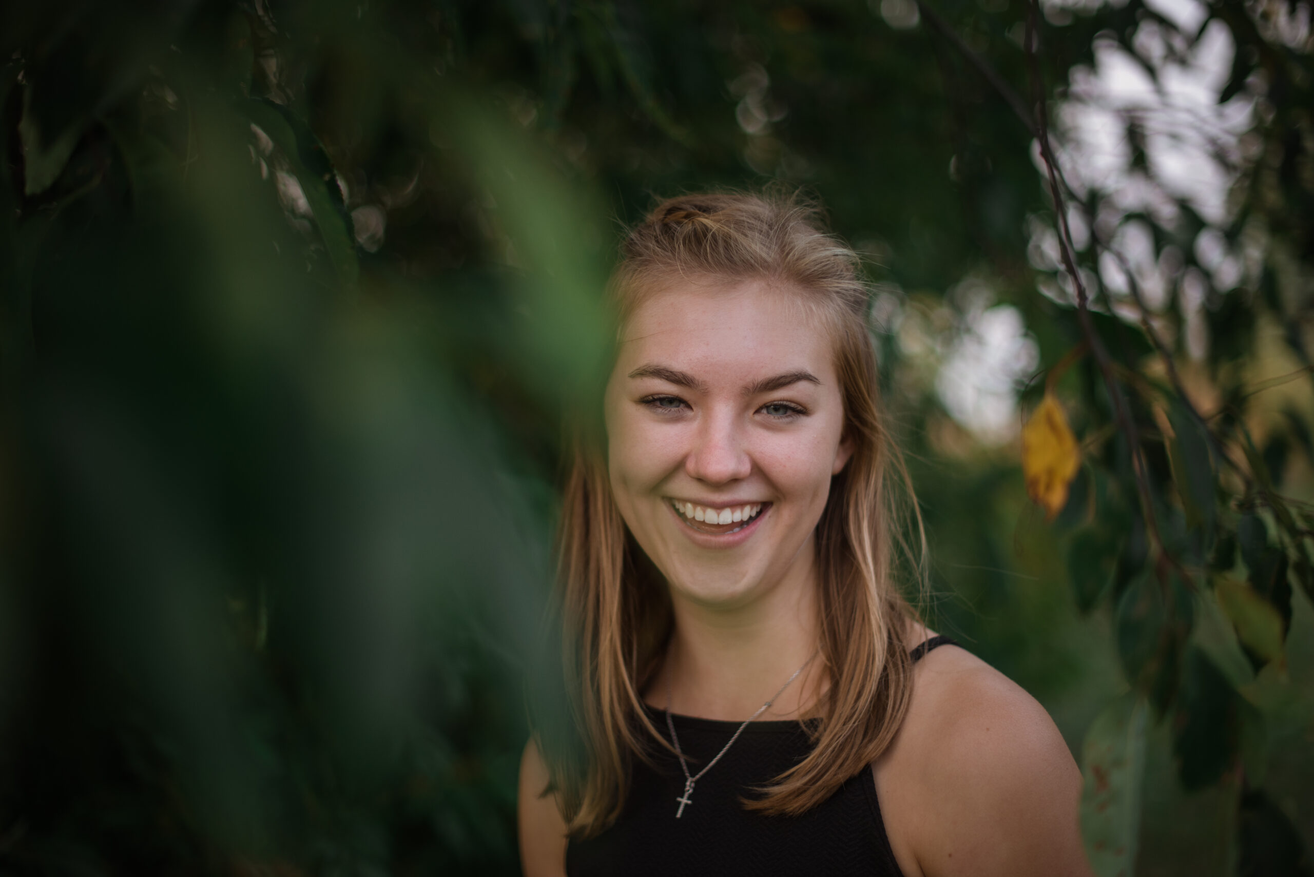 senior girl posing candid under a willow tree outside in traverse city michigan