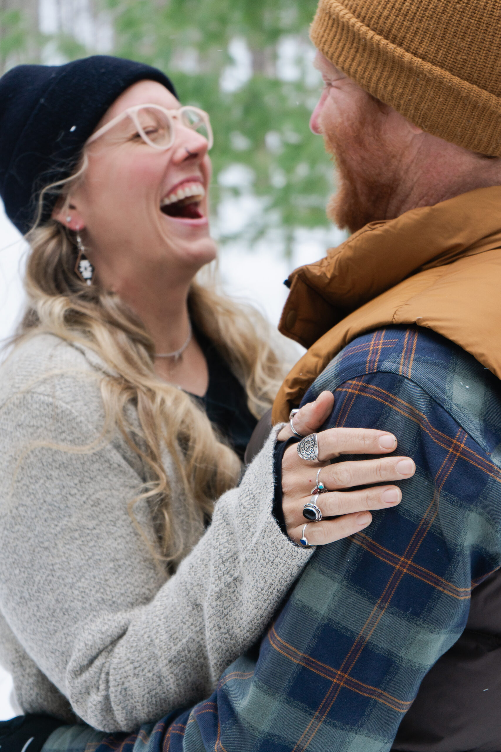 traverse city couple laughing during winter engagement photos in crystal lake michigan