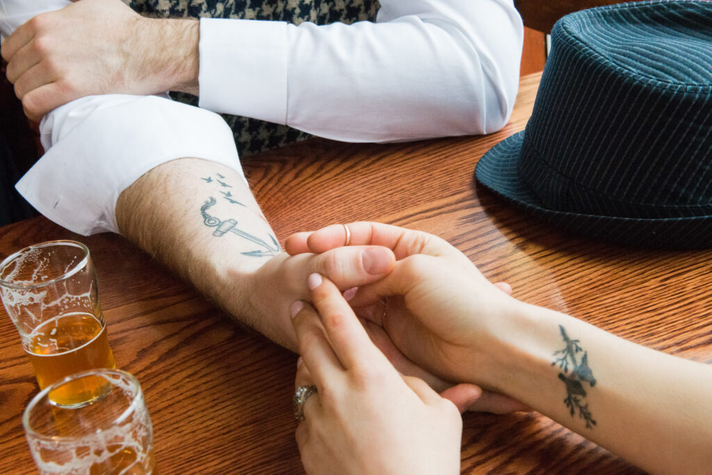 bride and groom holding hands at bar in downtown traverse city during engagement photos