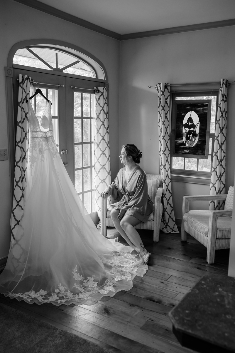 bride sitting looking out a window at blue sky barn in elmira michigan wedding