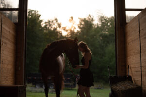 girl with her horse posing for senior pictures in barn in traverse city michigan