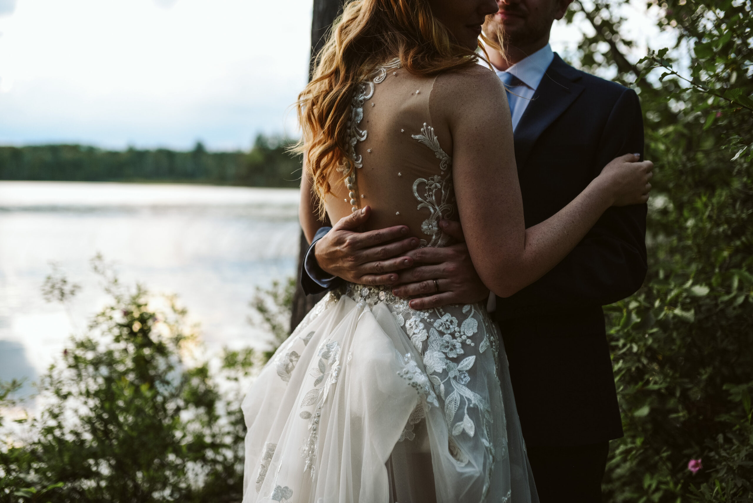 close up of grooms hands on brides back at blue bridge wedding in interlochen michigan wedding photographer