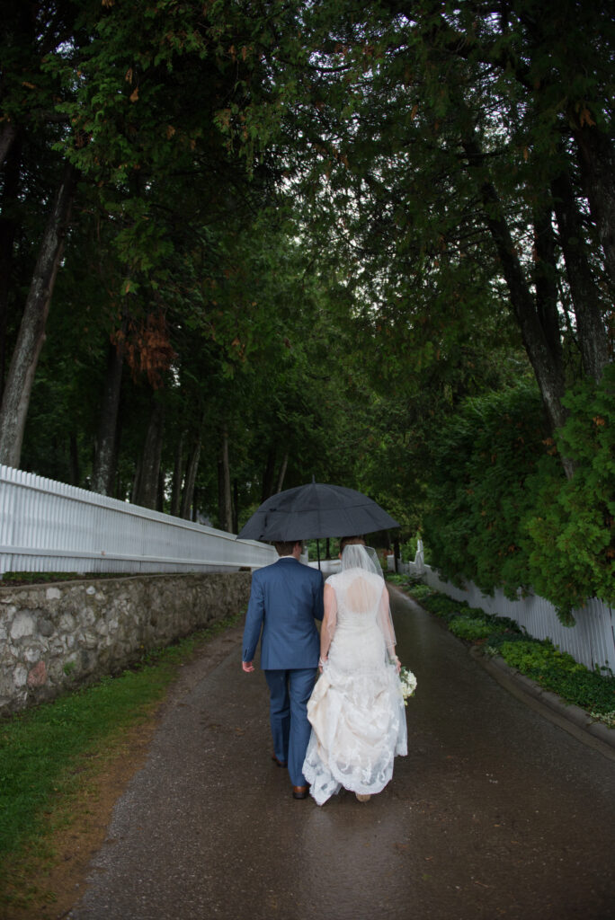 traverse-city-wedding-photographer bride and groom walking on mackinac island in rain northern michigan wedding photographer