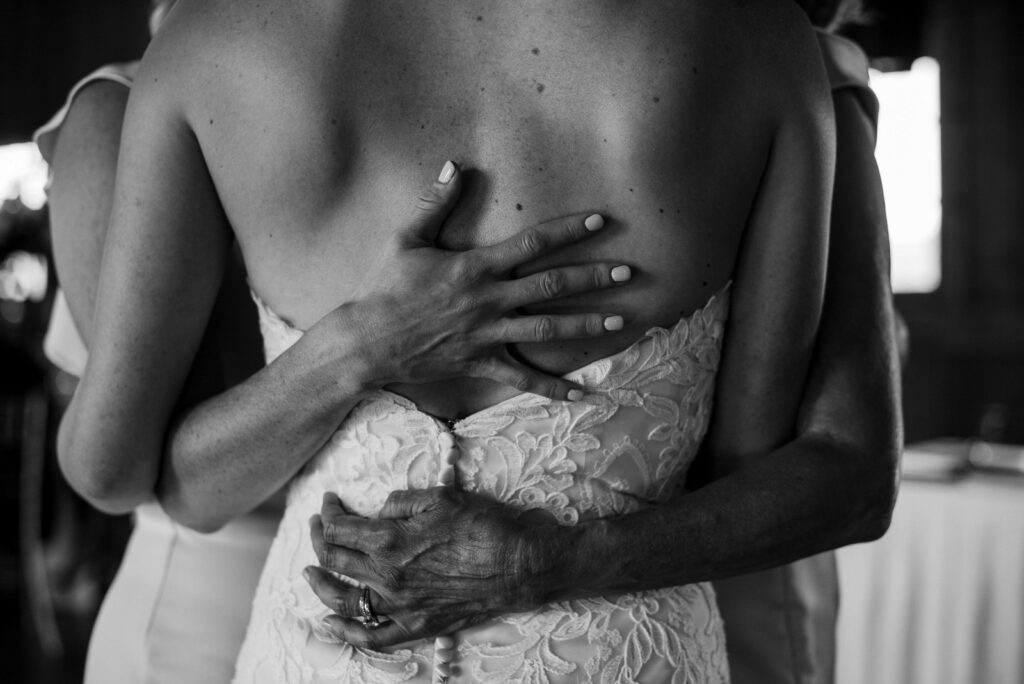 bride with her mother and sisters hands on her back in black and white traverse city wedding photography