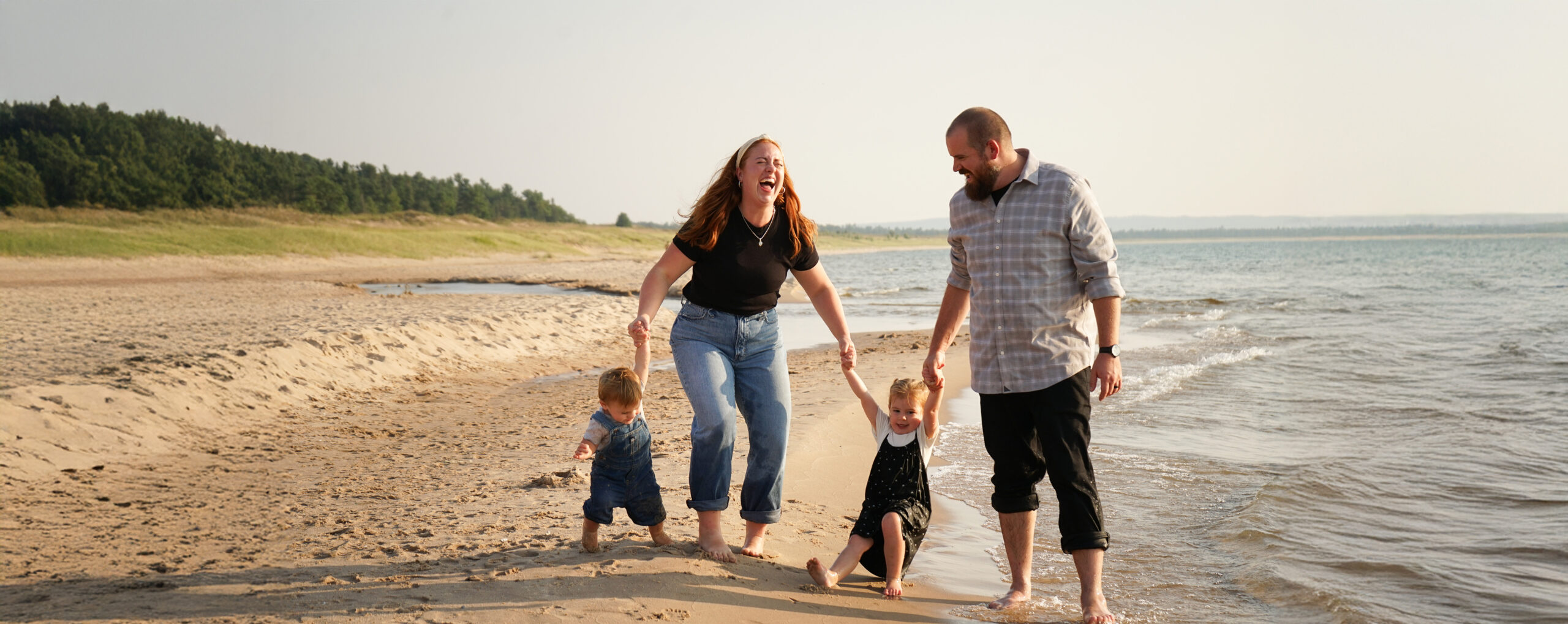 family playing on a lake michigan beach together in empire during family photos 