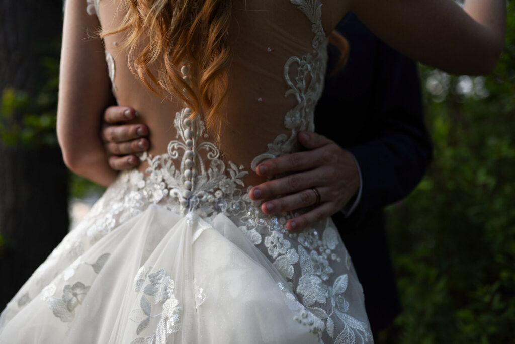 grooms hands on brides back during sunset at blue bridge event center wedding in traverse city michigan wedding photography
