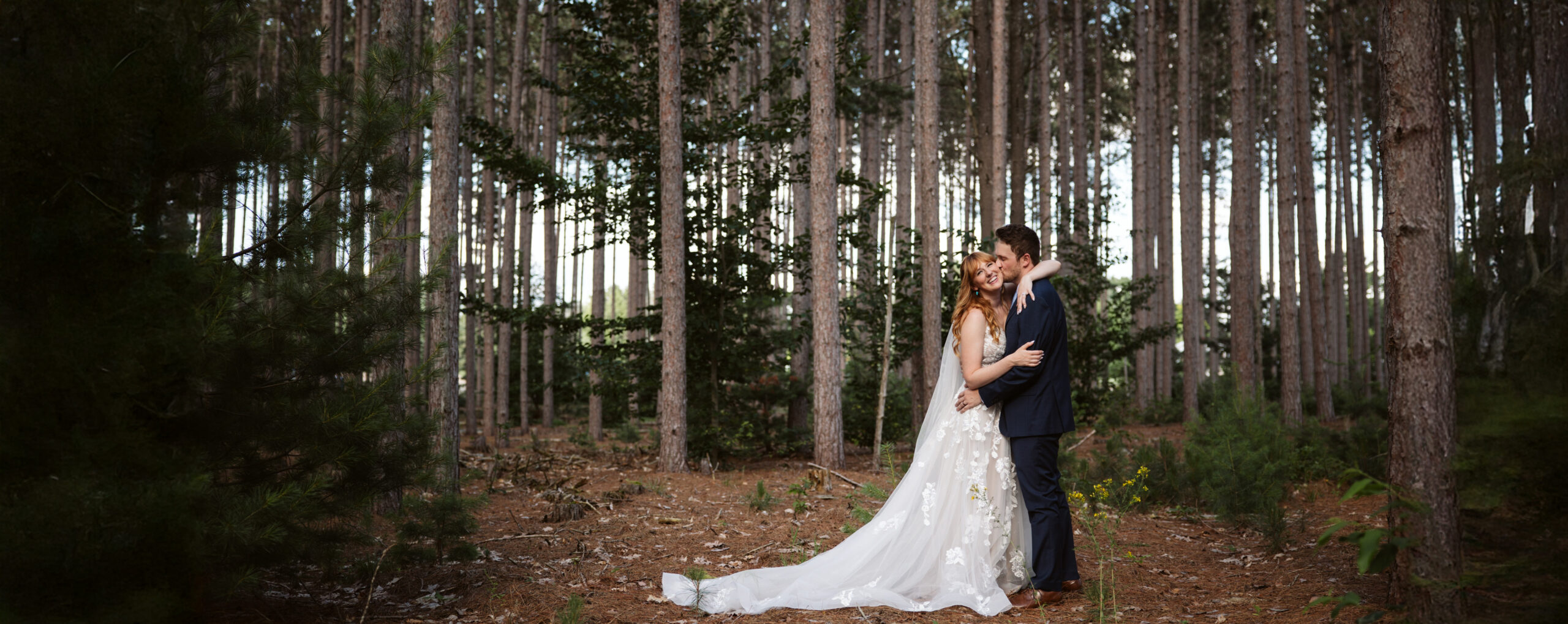 bride and groom laughing and kissing  in woods in traverse city wedding