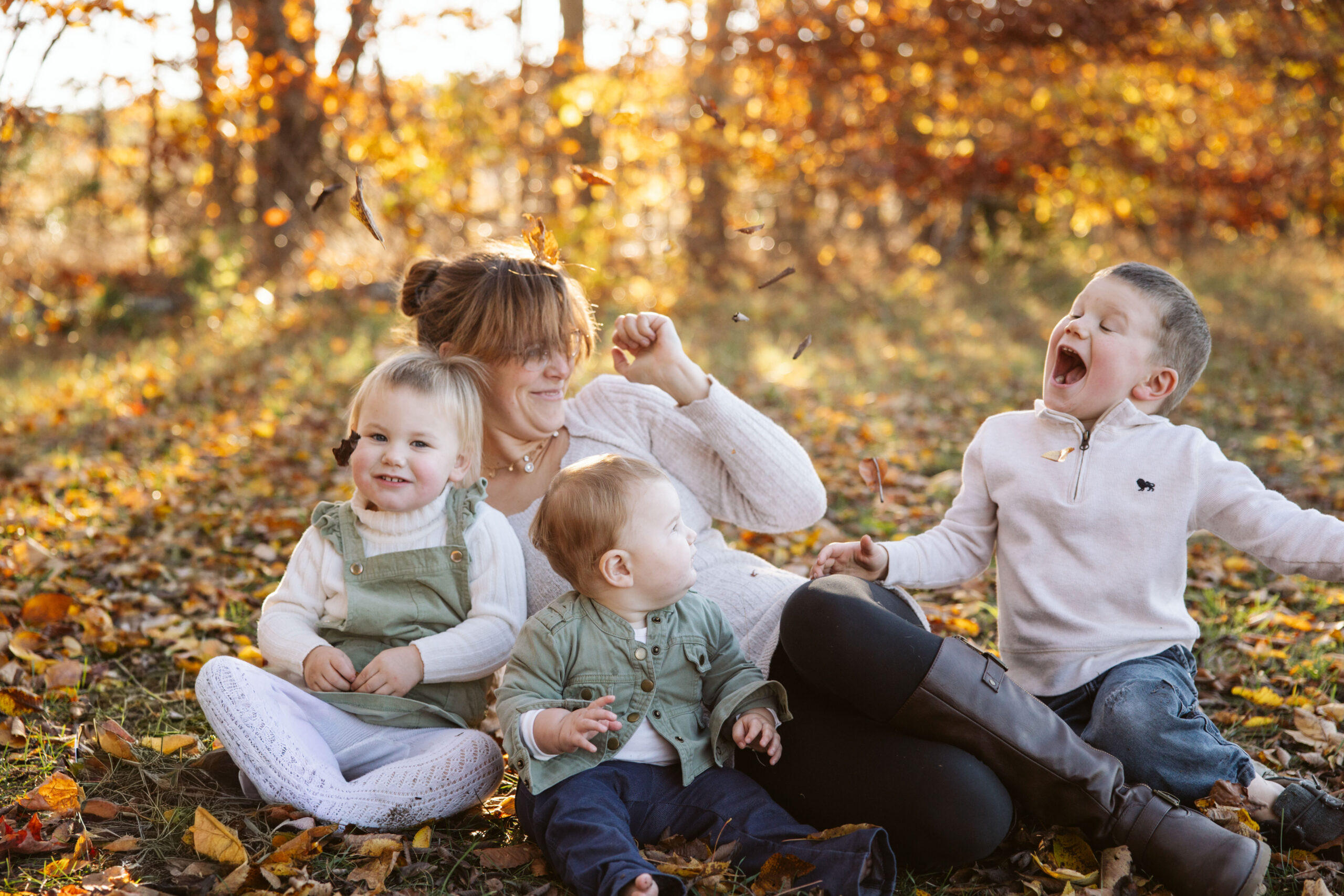 mother laying down in fall leaves with children during fall family photos in traverse city