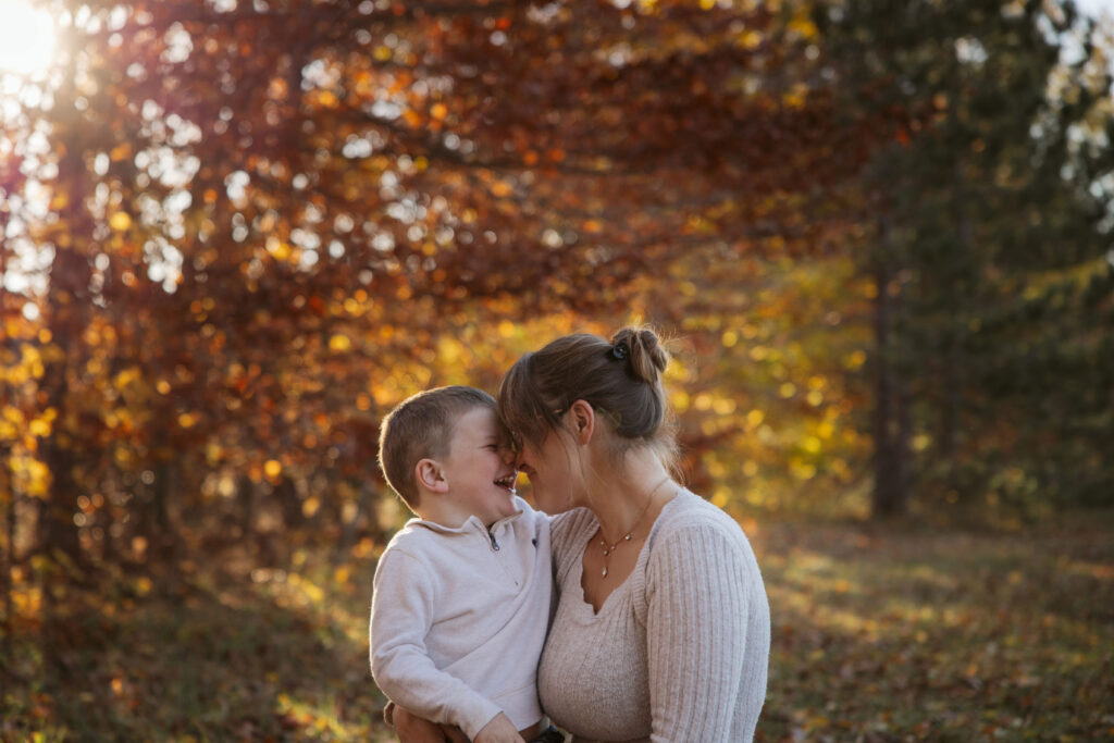 mother and son cuddling in a fall field during family pictures in empire michigan. Photo taken by traverse city photographer