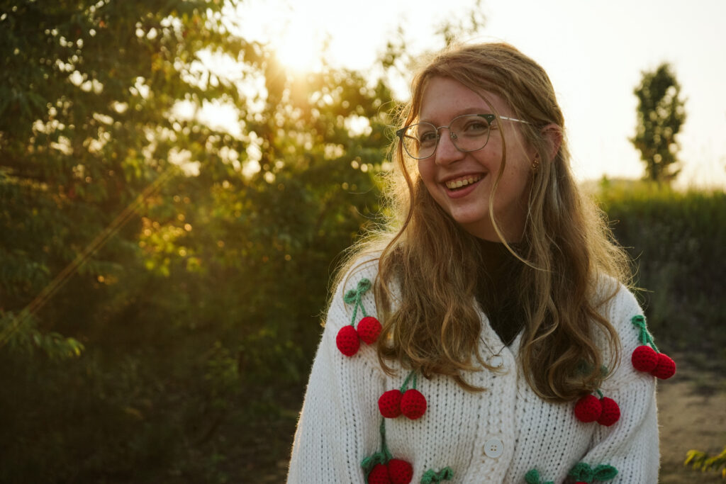 Girl standing in a field at golden hour during Senior photos. Photo by Traverse city photographer, Lina LaVonne Photography
