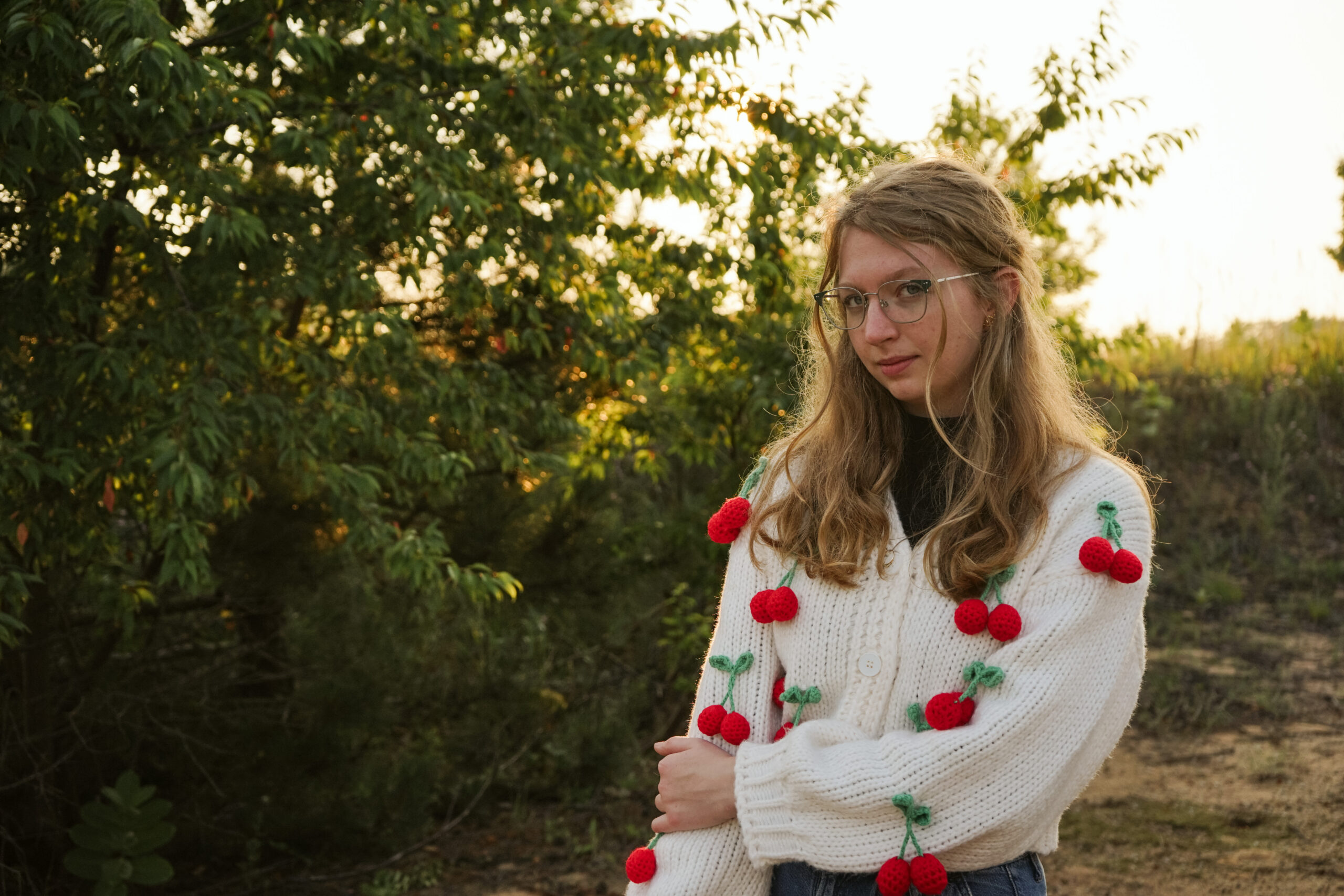 Girl standing in a field at golden hour during Senior photos. Photo by Traverse city photographer, Lina LaVonne Photography