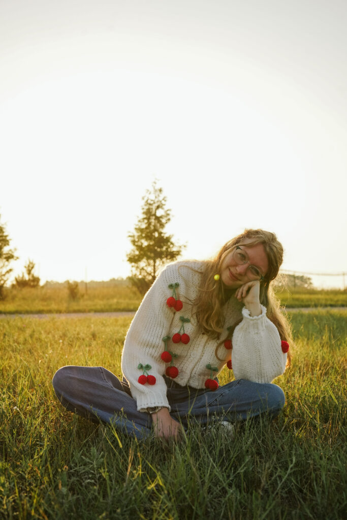 Girl standing in a field at golden hour during Senior photos. Photo by Traverse city photographer, Lina LaVonne Photography