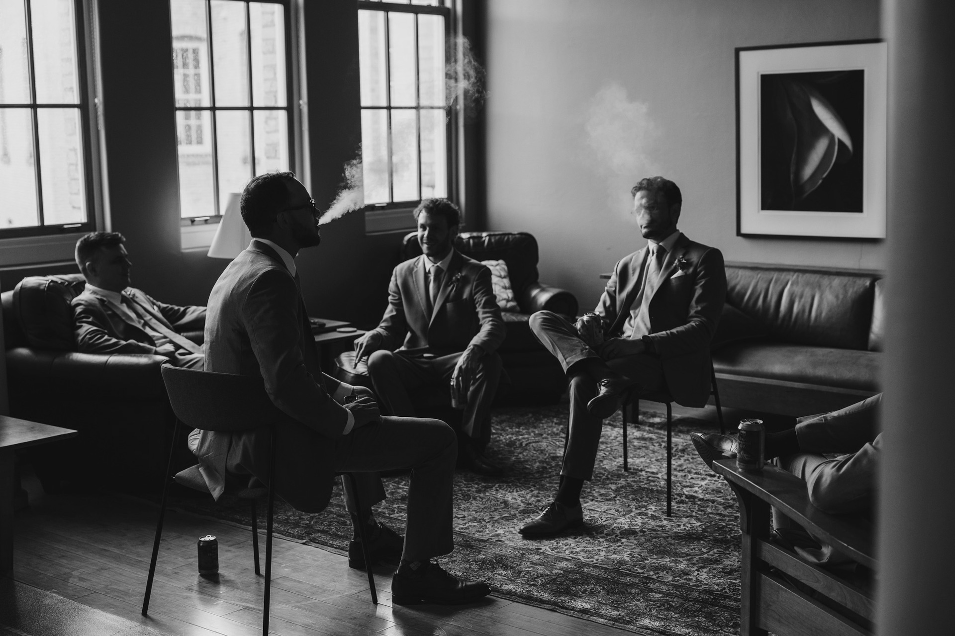 groom and groomsmen sitting smoking together at traverse city wedding