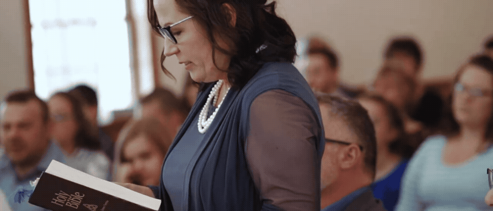 mother of the groom reading scripture during wedding in kalkaska michigan. video by traverse city wedding videographer
