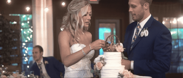 bride and groom cutting their cake and the groom tries to put cake on the brides face. video by traverse city wedding videographer