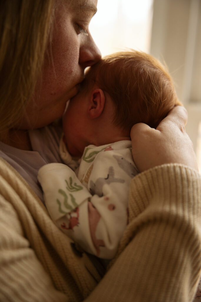 close up of mother. kissing baby during home newborn session in traverse city michigan