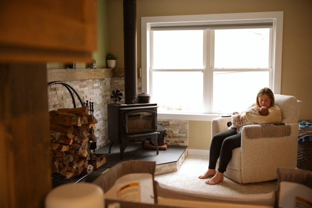mother sitting in a chair holding a newborn baby fduring family photos in traverse city michigan