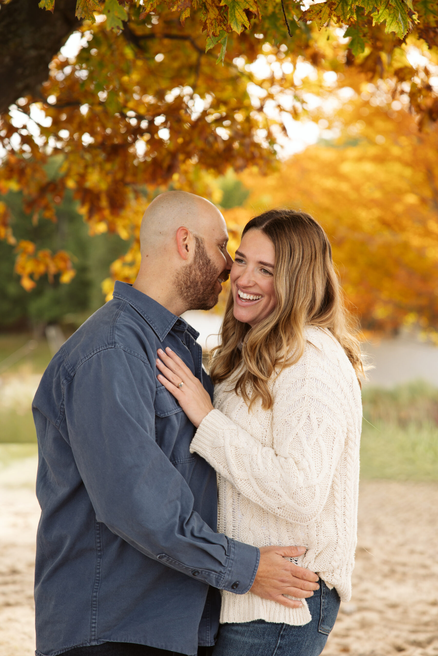 Husband and wife laughing during family pictures on empire beach. Photo by Lina Lavonne photography a traverse city photographer