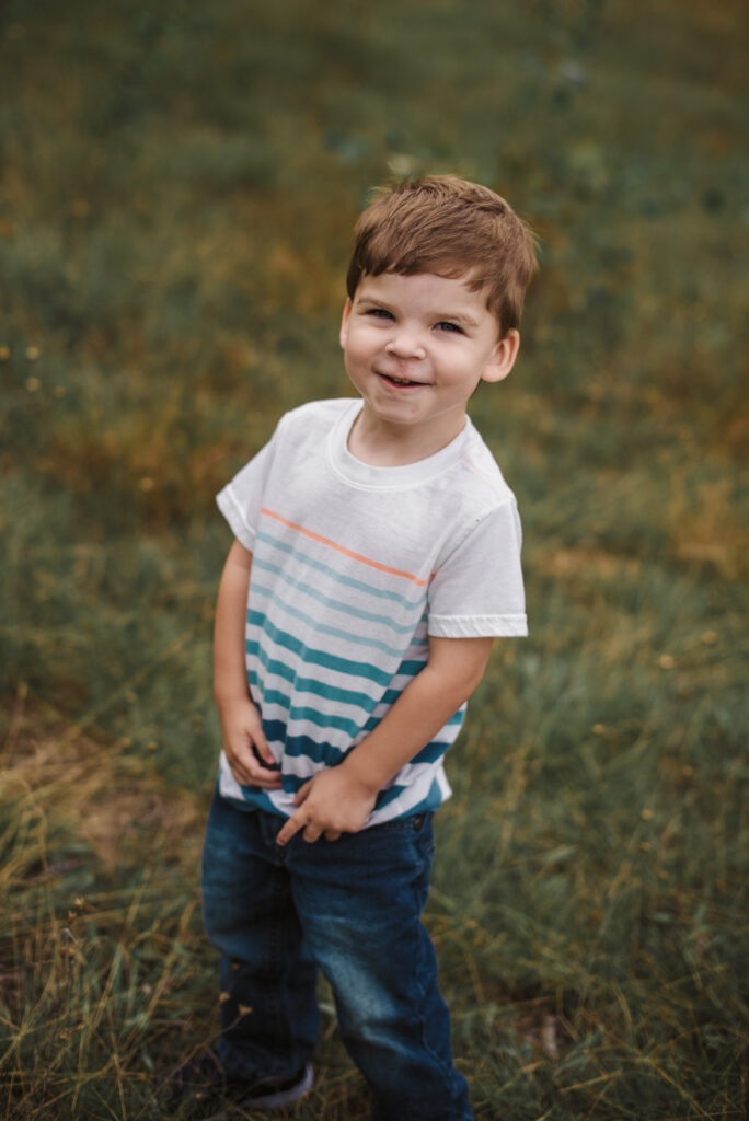 little boy laughing in field in traverse city during family portraits