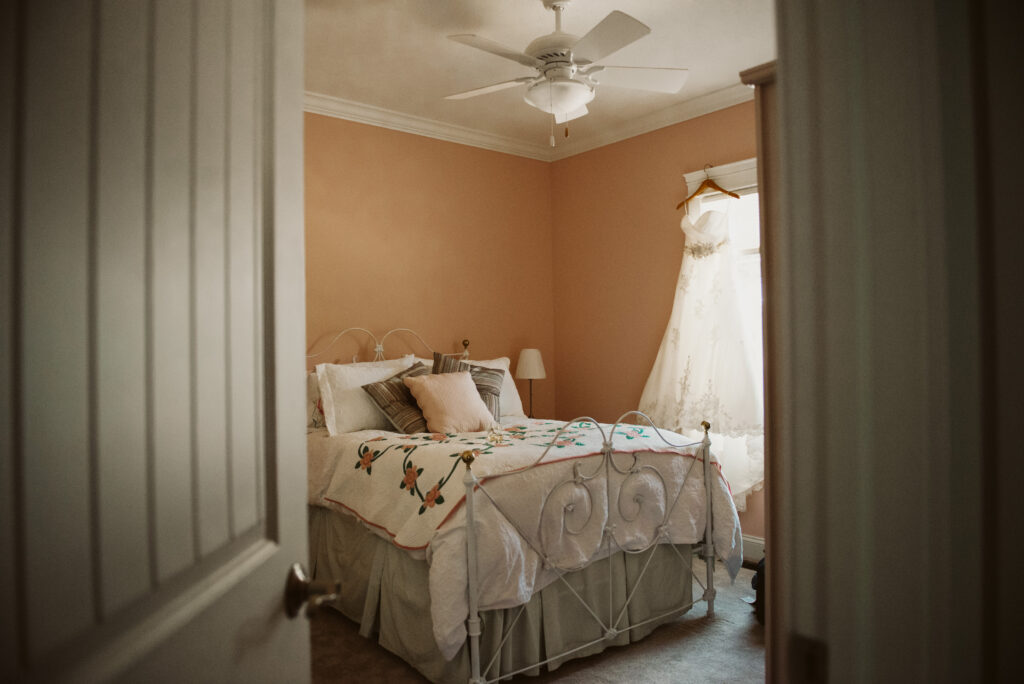 wedding dress hanging in pink bedroom before traverse city wedding. Photo by traverse city wedding photographer lina lavonne photography