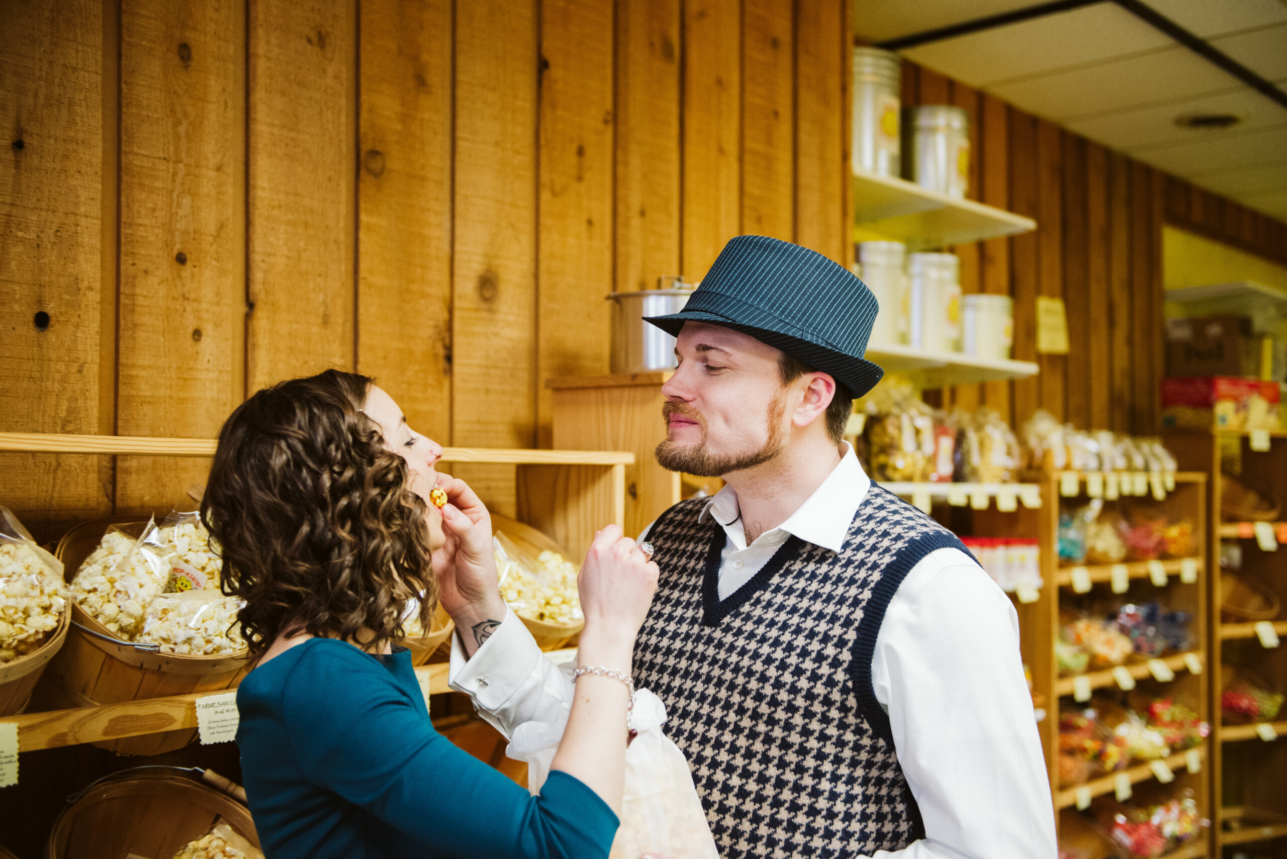 Bride and groom feeding each other popcorn at store downtown traverse city during engagement photos. Photo by Traverse City Photographer Lina LaVonne Photography