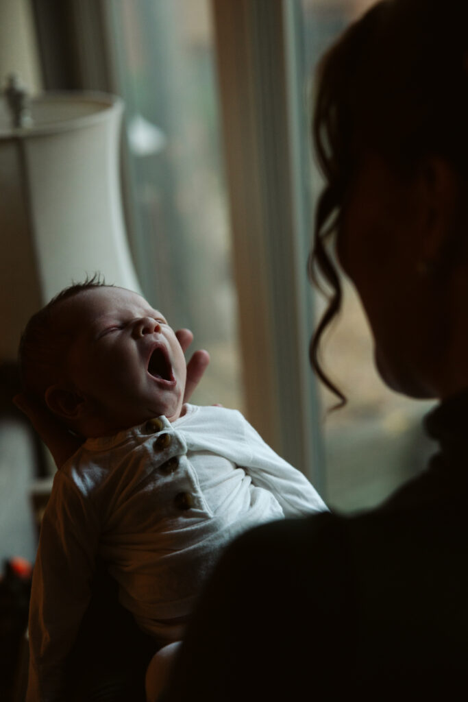 baby yawning in the arms of his mother during newborn photos in traverse city. Photo by Traverse City Photographer Lina Lavonne Photography