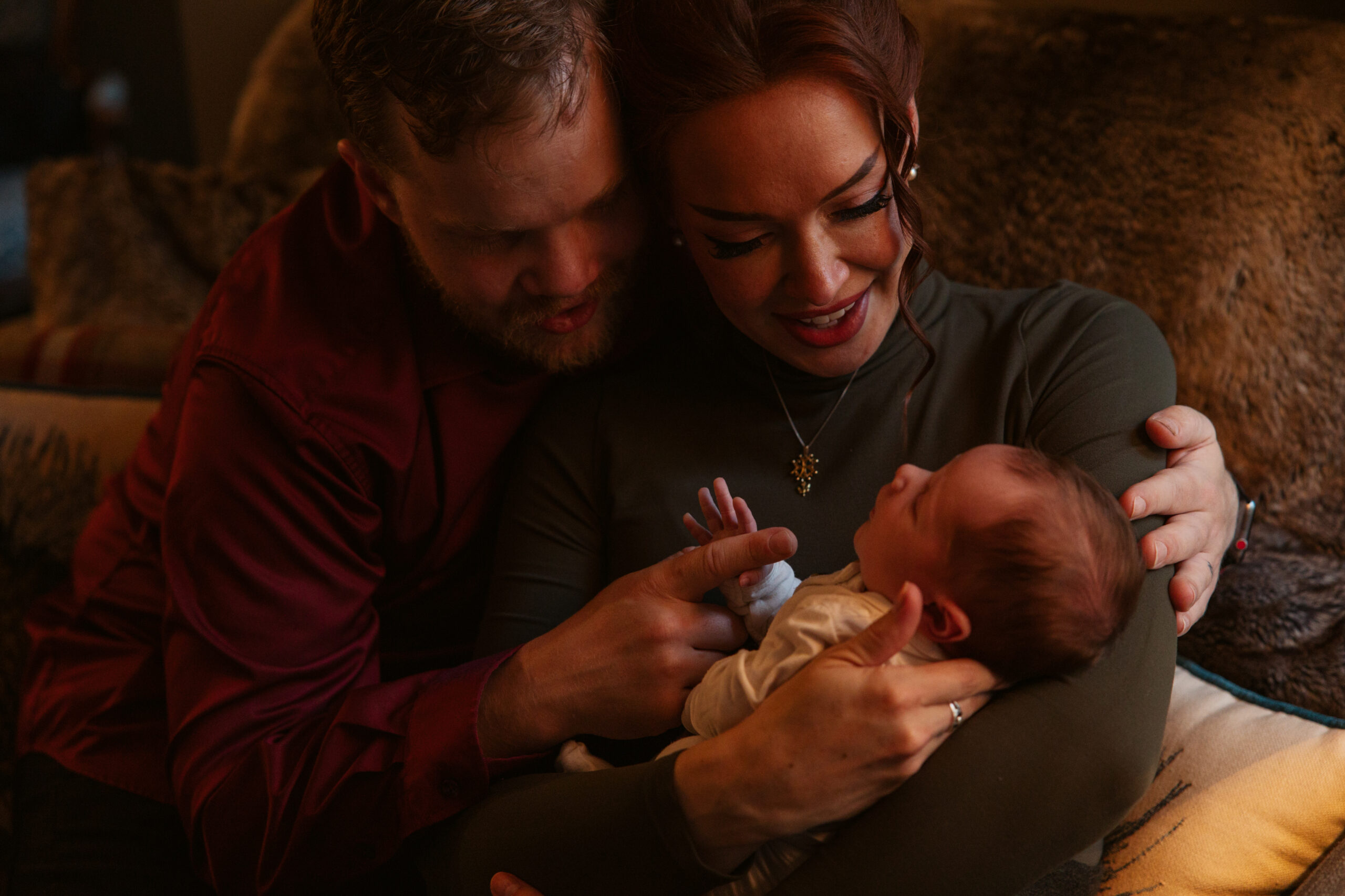 baby in the hands of his mother and father during in home newborn photos in traverse city. Photo by Traverse City Photographer Lina Lavonne Photography