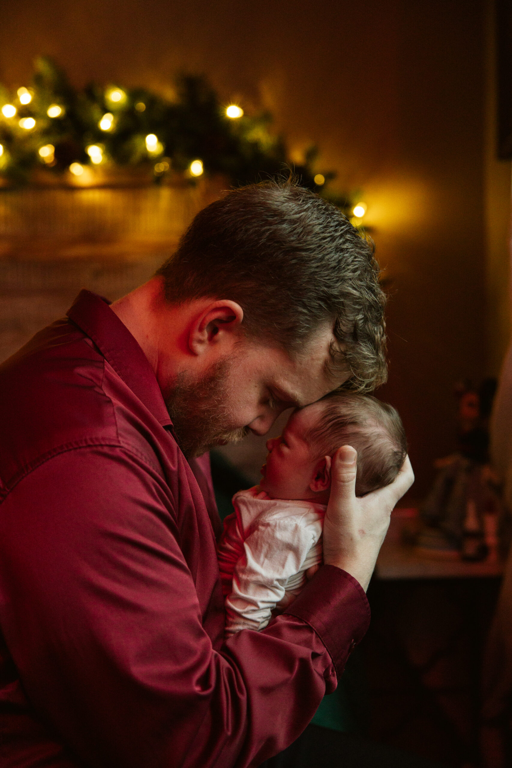 dad holding baby close to his head during newborn photos in traverse city. Photo by Traverse City Photographer Lina Lavonne Photography