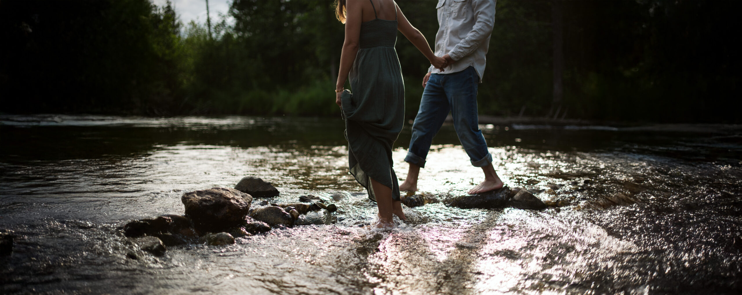 close up of man and woman holding hands in a river during traversecity engagement session