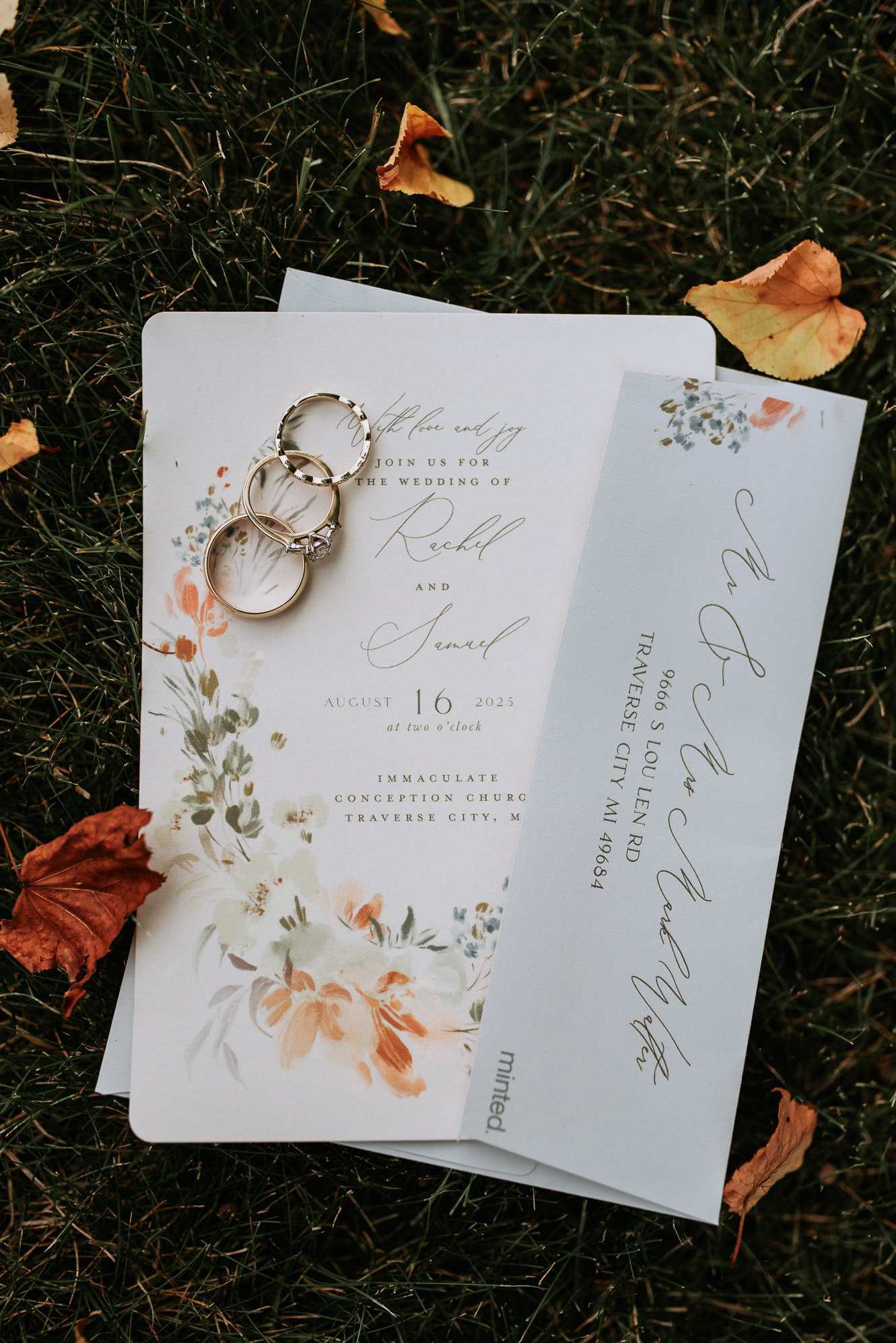 traverse-city-wedding-photographer-2 wedding invitations and rings sitting in the grass at private home in northern michigan. Photo by traverse city wedding photographer lina lavonne photography